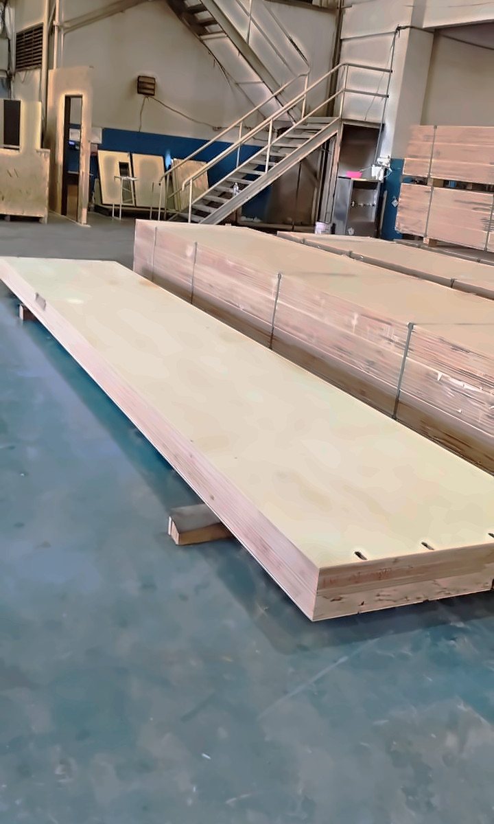 A long 180 millimetre multi-glued LVL panel lying on the factory floor, with slots cut along one edge