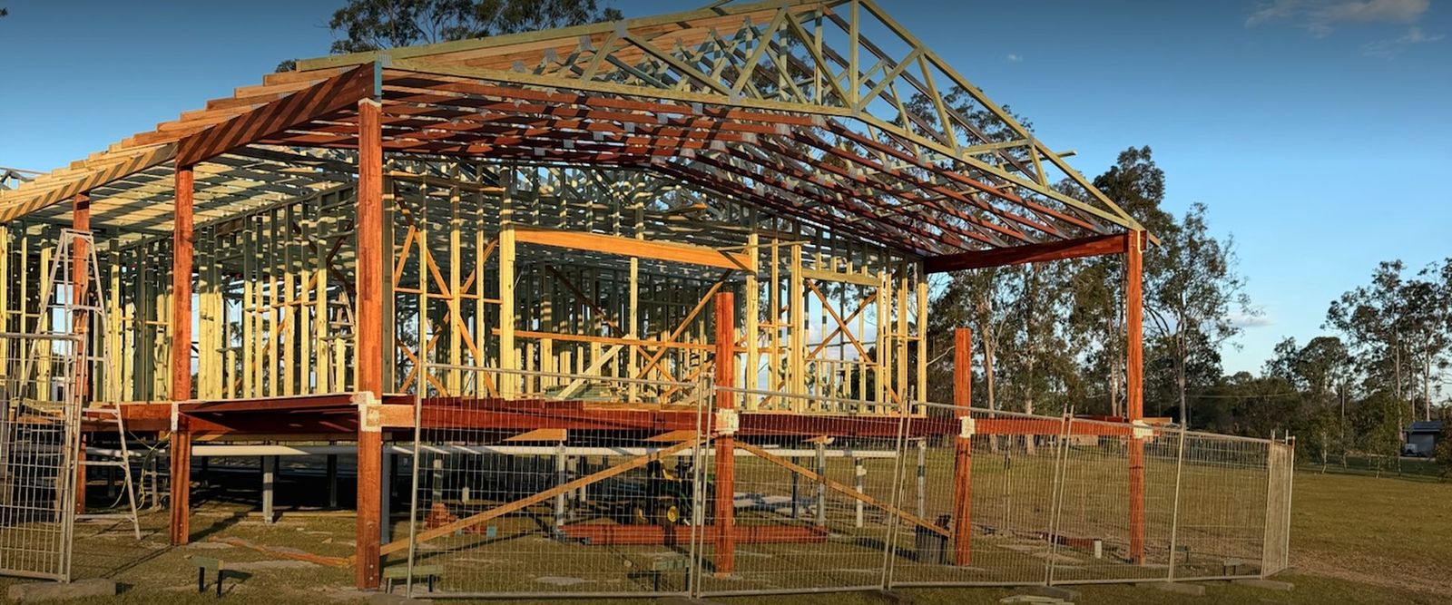 Elevated timber house frame with trusses under construction at golden hour